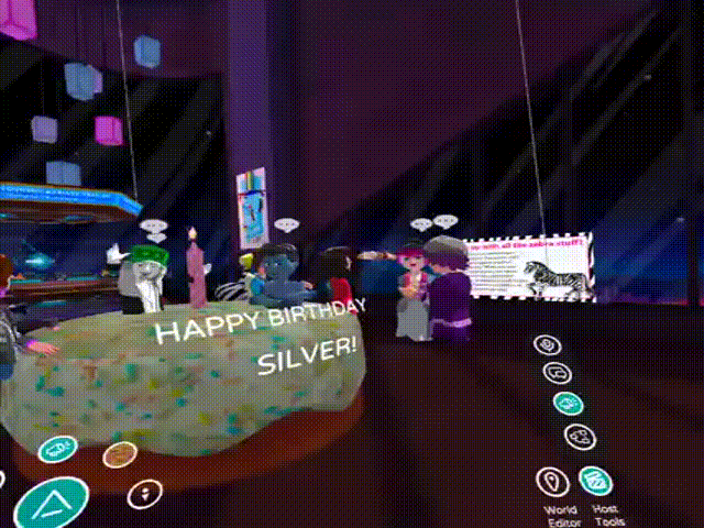 This is a GIF image that shows a birthday party in Altspace for one of our group members, SilverFoxtrot. There is a large virtual birthday cake and all of the cartoon avatars who represent group members are walking in and out of the cake, and Silver gives me a virtual hug. At the end of the GIF, a camera light flashes as I take a picture of the moment. 